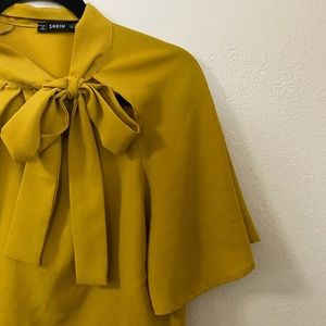 She In- Vibrant mustard yellow bow tie shirt.